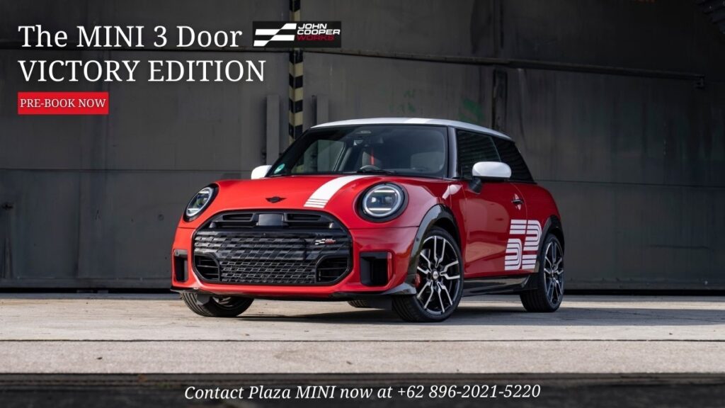 Red MINI 3 Door John Cooper Works Victory Edition parked in industrial setting with promotional pre-book banner and contact number