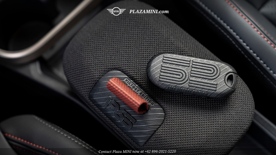 Two black 59 Victory Edition car key covers with textured lines and a red accent, placed on a black car seat with red stitching.